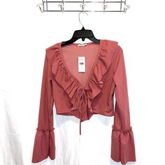 Stand Out In A Sophisticated Number With This Long-Sleeved Ruffle Frill Top. Featuring A Plunge Neckline With Tie Detailing, This Sassy Crop Is The Perfect Choice For A Classy Night Out. Pair With A Bodycon Midi Skirt And Heels To Complete The Elegant Look. Rose Pink / Mauve Pink Long Sleeve Ruffle/Frill Details Around Neckline And On Sleeves Cropped Plunge Neckline Tie Feature On Bust 96% Polyester 4% Spandex Spring Ruffle Hem Top For Night Out, Ruffle Hem Tops For Spring Night Out, Ruffle Hem Top For Night Out In Spring, Flirty Long Sleeve Blouse For Spring, Spring Night Out Blouse With Ruffle Hem, Spring Ruffle Hem Blouse For Night Out, Trendy Ruffled Tops For Date Night, Flirty Ruffled Tops For Fall, Flirty Ruffled Blouse For Brunch