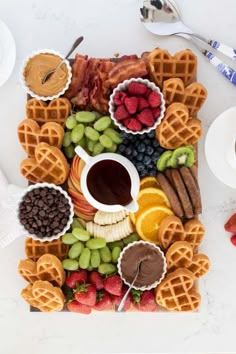 a platter with waffles, fruit, chocolate and other foods on it