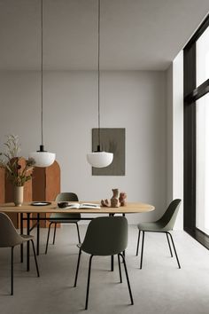 a dining table with four chairs in front of a large window and a potted plant next to it