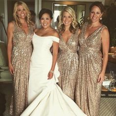 three women in gold dresses posing for the camera with one woman wearing a white dress