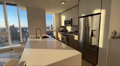 an empty kitchen with stainless steel appliances and large windows looking out on the cityscape