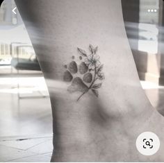 a dog paw and flower tattoo on the side of a woman's foot,