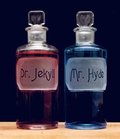 two bottles of dr jekyll and mr hyde perfumes on a wooden table