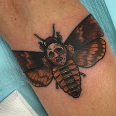 a close up of a person's arm with a tattoo on it and a skull in the shape of a bee