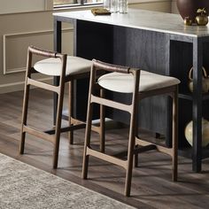 two stools sitting in front of a counter with a vase on top of it