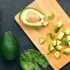 an avocado cut in half on a cutting board next to other fruits and vegetables