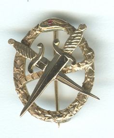 a gold brooch with two crossed swords in the center and an arrow on top