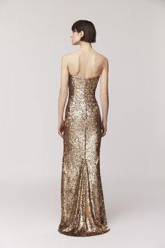 a woman in a gold sequinned gown looking back at the camera with her hands on her hips