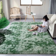 a woman sitting on top of a green rug