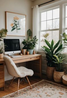 a home office with plants and a computer on a desk in front of a window