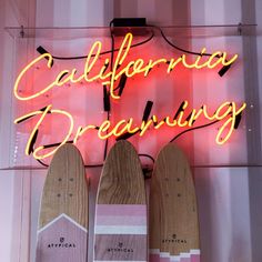 two snowboards are standing next to each other in front of a neon sign that reads california dreaming