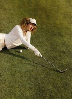 a woman is laying on the grass playing golf