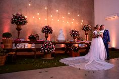 a newly married couple standing in front of a table with flowers and candles on it