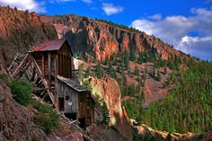 an old wooden building sitting on the side of a mountain