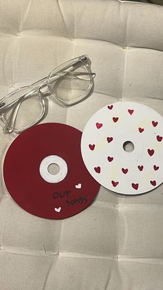 two cd cases with hearts on them sitting next to each other and one has a pair of glasses