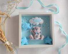 a teddy bear sitting in a box with blue stars on the sides and a baby's name tag attached to it