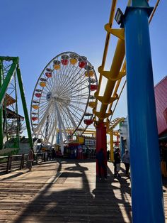 an amusement park with a ferris wheel in the background and people walking on the boardwalk