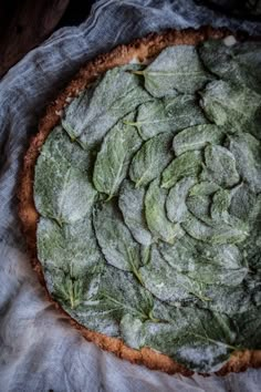 a pizza covered in leafy greens on top of a table