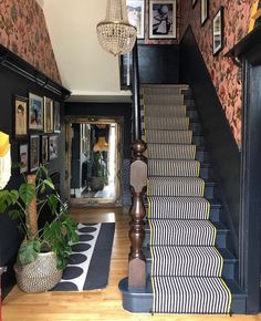 the stairs are decorated with black and white striped rugs, potted plants, and pictures on the wall