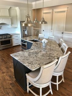 a large kitchen with an island and marble counter tops in the middle of the room