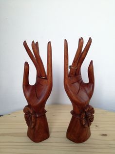 two wooden hand sculptures sitting on top of a table