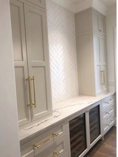 an empty kitchen with marble counter tops and gold pulls on the cabinets, along with wooden floors