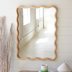 a mirror sitting on top of a wooden table next to a vase and other items