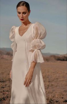 a woman standing in the desert wearing a white dress