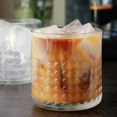 an iced drink in a glass with ice cubes on the table next to it