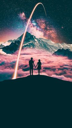 two people holding hands while standing on top of a mountain with a rocket in the sky