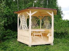 a small wooden gazebo sitting on top of a lush green field