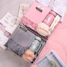 the contents of a pink gift box are laid out on top of a bed sheet