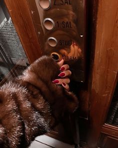 a woman with red nails is leaning against a door and touching the handle on an elevator