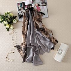 Elevate your style with our Silky Satin Oblong Scarf. Each scarf is carefully chosen to add elegance and sophistication to your everyday attire and special events. Made from premium silky satin, this scarf is lightweight, soft, and boasts a subtle shine for a glamorous touch. With a variety of beautiful designs, chic patterns, and stunning colors, each scarf is a work of art. Whether it's keeping you warm and cozy in the winter or cool and stylish in the summer, this long oblong scarf is the per Poncho Winter, Winter Cape, Beach Shawl, Silk Scarf Wrap, Silk Scarf Style, Chiffon Hijab, Pure Silk Scarf, Luxury Scarves, Scarf Women Fashion