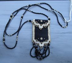 Black beaded amulet bag necklace - This is a small, elegant necklace.  The amulet bag itself is only 1 1/2 X 2 inches with an inch of black beaded fringe.  The bag is of mostly black beads with gold and white beads in a lovely design.  The bag has a flap over the top which mirrors the bottom design.  The necklace strap is made of black beads with gold and white beads interspersed.  I've made this bag a couple of times - one for a wonderful woman who had lost all of her jewelry and everything else in a fire.  It was a nice addition to her black dress she wore for a choir concert.  This was made with Miyuki Delica beads. Everyday Black Beaded Jewelry, Black Beaded Necklace With Gold Beads As Gift, Black Pendant Necklace For Everyday Use, Black Handmade Beaded Necklaces For Evening, Black Amulet Style Beaded Necklaces, Black Rectangular Beaded Jewelry, Black Bohemian Necklace For Everyday Use, Black Bohemian Necklace For Everyday, Elegant Black Necklace For Everyday Use