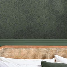 a bed with green wallpaper and pillows in front of a wooden headboard against a dark green wall