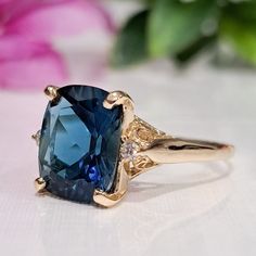 5.60 Carat Natural London Blue Topaz & Diamonds 14k Solid Gold Ring  Ring Material: 14k Solid Gold  Total Metal Weight: 3.8 Grams  Gemstone: Natural London Blue Topaz Gemstone Color: Dark Blue  Gemstone Shape: Cushion Gemstone Dimensions: 12.00x10.00 mm Gemstone Carat Weight: 5.52 Carat Gemstone Quantity: 1 Natural Round Shaped Diamonds Diamonds Quantity: 2 Diamonds Total Carat Weight: 0.08 Carat Total Carat Weight: 5.60 Carat Ring Quantity: One  Condition: New Delivered in an elegant gift box M Formal Sapphire Birthstone Ring With Accent Stones, Blue Birthstone Diamond Ring For Formal Occasions, Formal Blue Diamond Ring With Birthstone, Formal Blue Sapphire Ring With Birthstone, Formal Blue Tanzanite Birthstone Ring, Formal Blue Sapphire Birthstone Ring, Formal Blue Birthstone Diamond Ring, Blue Diamond Ring With Gemstone Accents, 14k Gold Blue Sapphire Ring With Center Stone