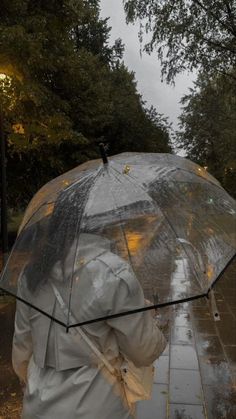 a person walking down the street in the rain with an umbrella over their head while it's raining