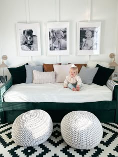 a baby sitting on top of a bed in a room with two pictures above it