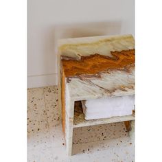 a white and brown marble side table sitting on top of a tiled floor next to a wall