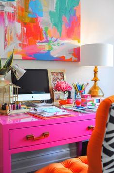 a pink desk with lots of colorful art on it