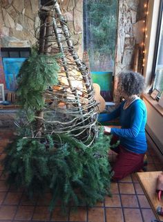 a woman sitting on the floor next to a christmas tree in front of a window