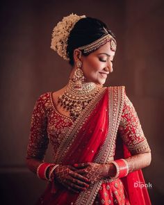 a woman in a red and gold bridal outfit with her hands on her hips