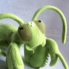 a green stuffed animal sitting on top of a white surface