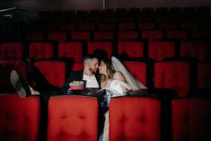 a bride and groom are sitting in an empty theater with their feet propped up on the seats