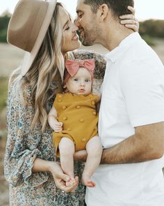 a man and woman holding a baby in their arms