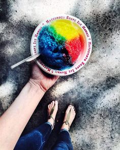 a person is holding a bowl of food with rainbow dye in it and their feet are on the ground