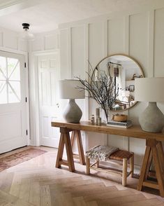 a table with two vases sitting on top of it next to a mirror and lamp