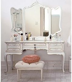 a white dressing table with a mirror and stool