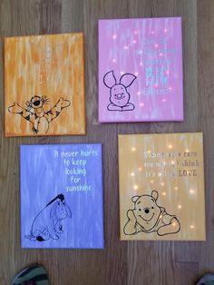 four winnie the pooh canvass on a wooden floor with lights in the background